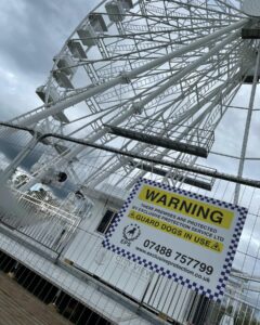 Image of Exclusive Protection Services placard placed on harris fencing around a ferris wheel
